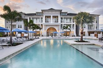 a large swimming pool with palm trees in front of a building