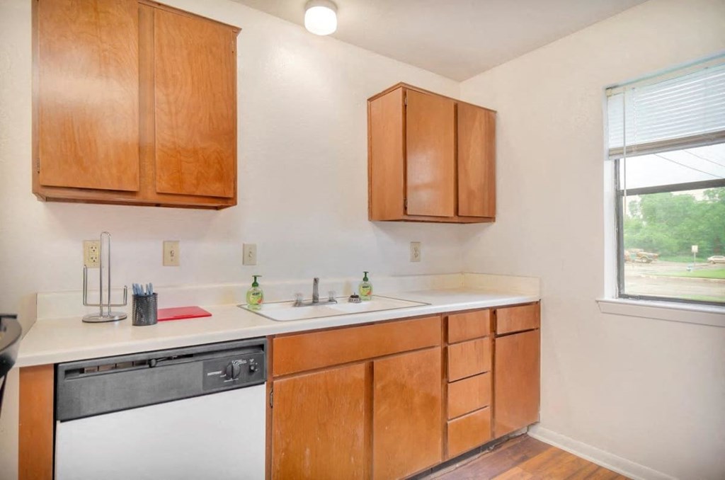 A kitchen with wooden cabinets and a white dishwasher.