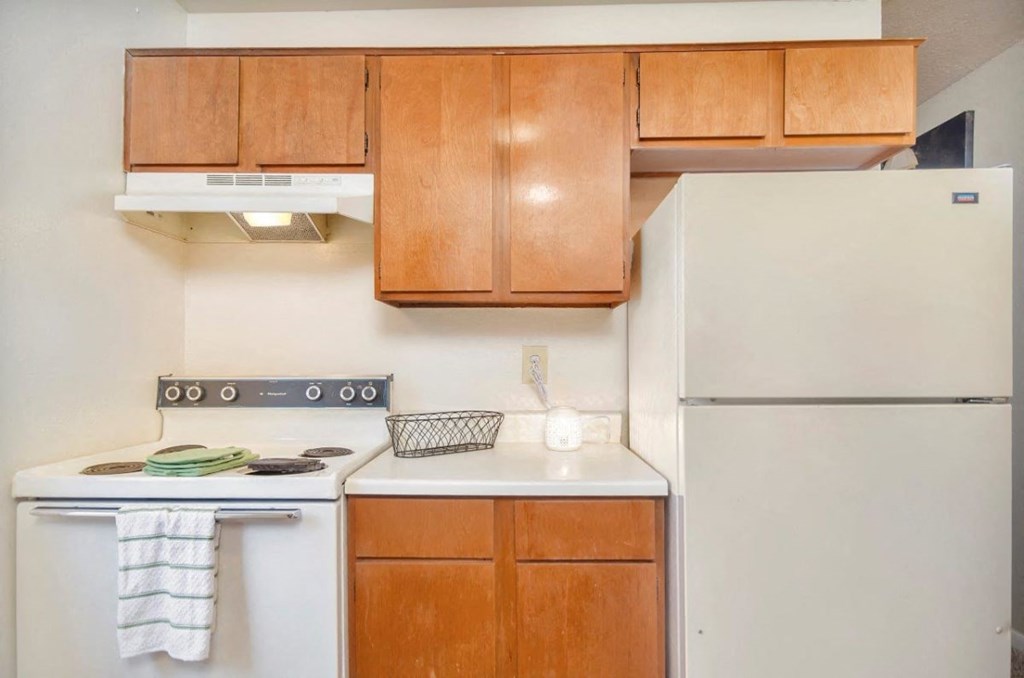 A kitchen with a white stove and a white refrigerator.