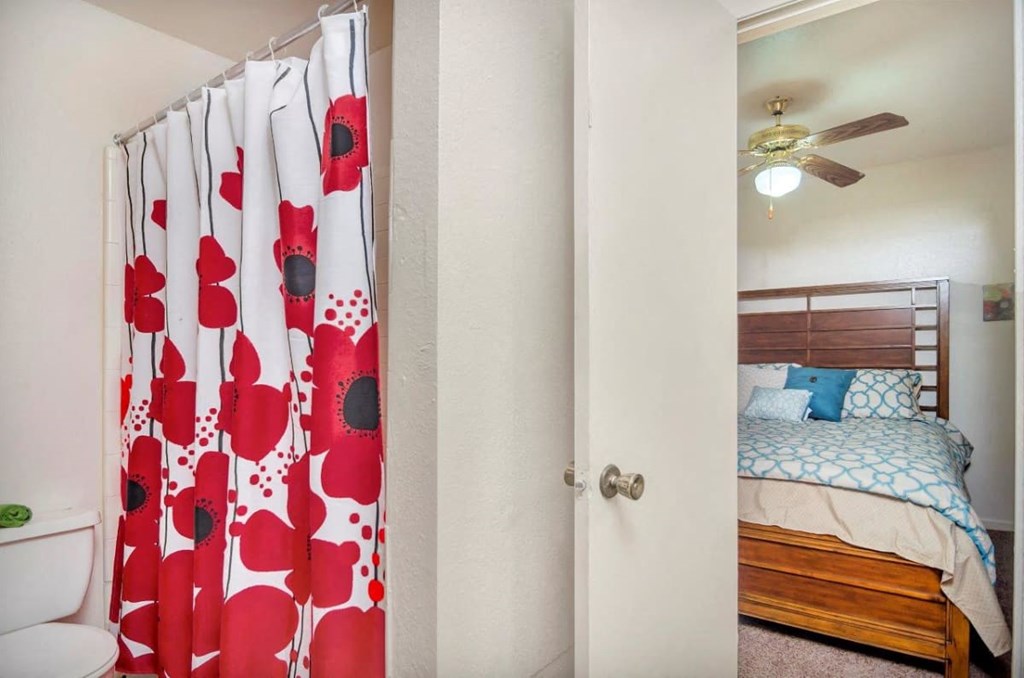 A bedroom with a bed and a shower curtain with red and black flowers.