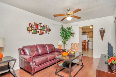 A living room with a red leather couch and a glass coffee table.