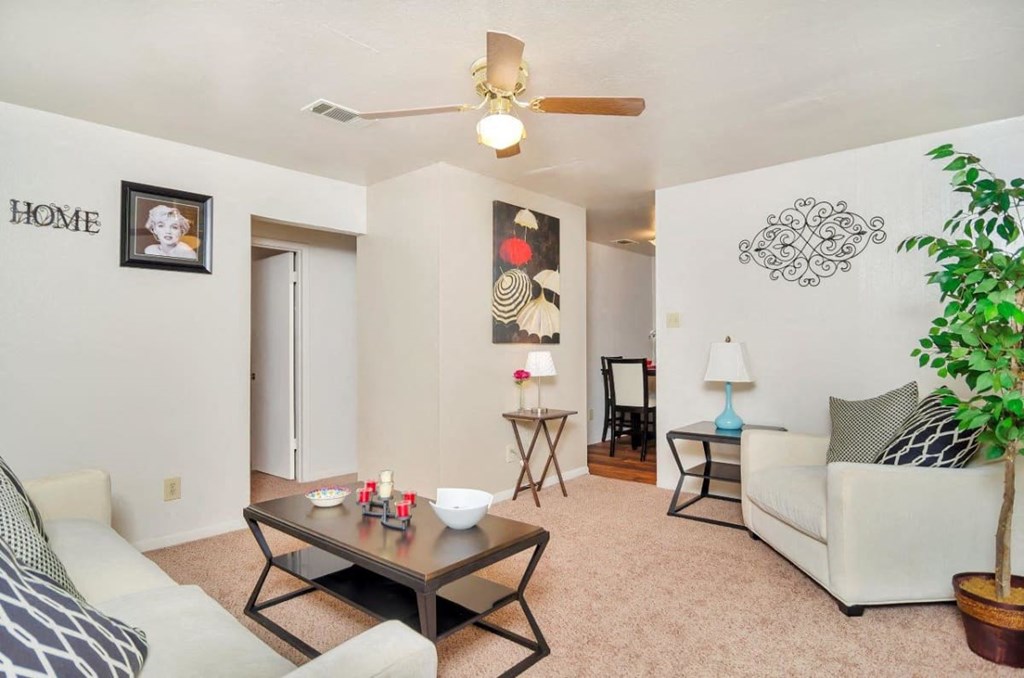 A living room with a couch, a coffee table, and a ceiling fan.