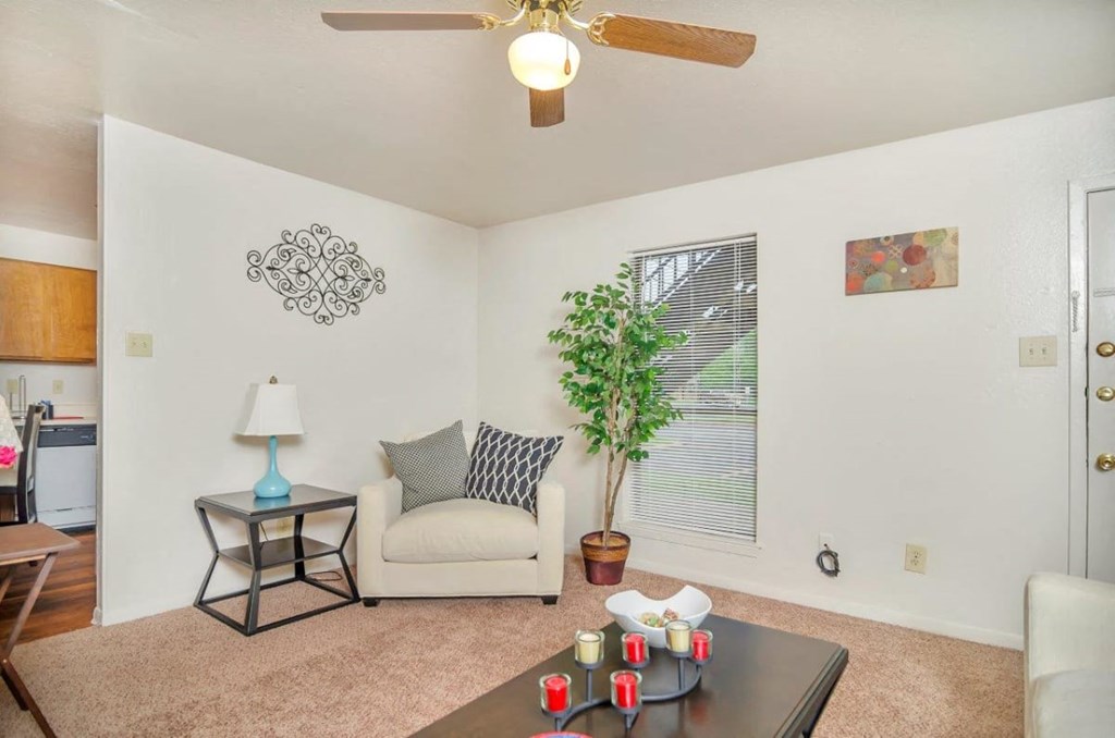 A living room with a couch, a table, and a ceiling fan.