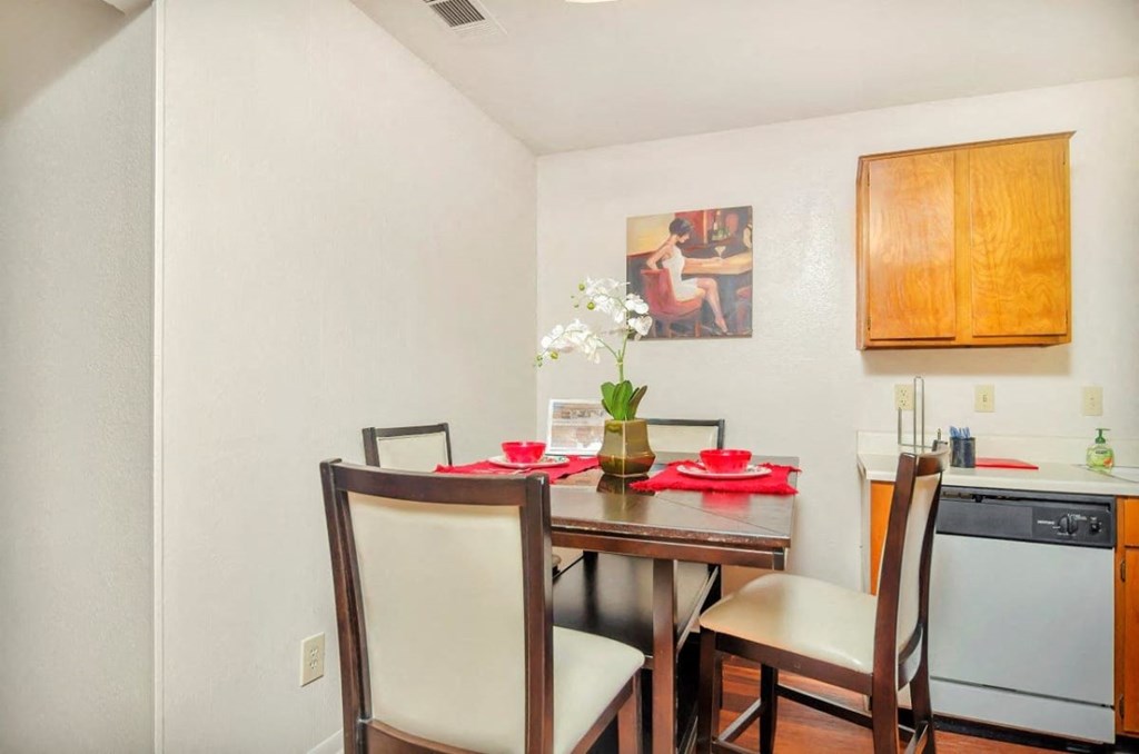 A dining room with a table set for two and a washing machine in the background.