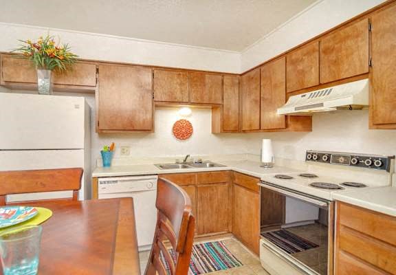 A kitchen with wooden cabinets and a white stove top oven.