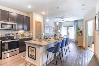an open kitchen and dining area with a large island and stainless steel appliances