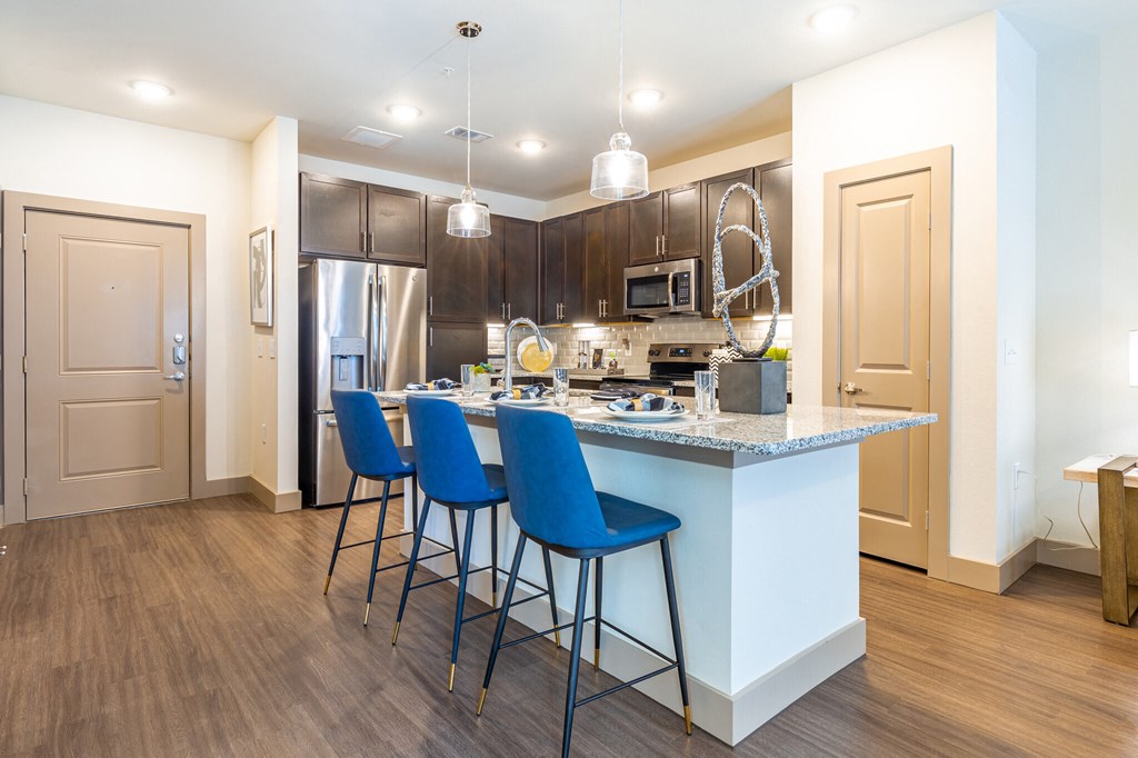 a kitchen with a large island with blue bar stools