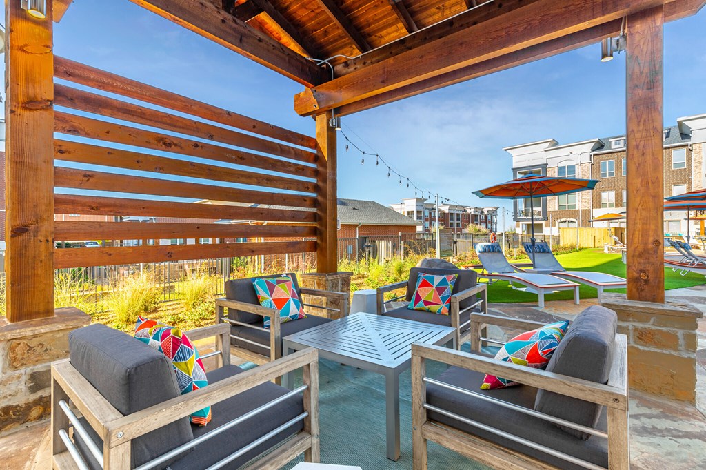 a patio with tables and chairs and a house in the background