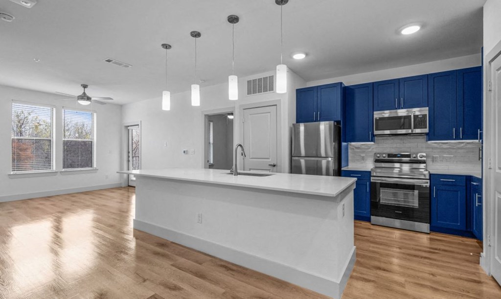an empty kitchen with blue cabinets and a white counter top
