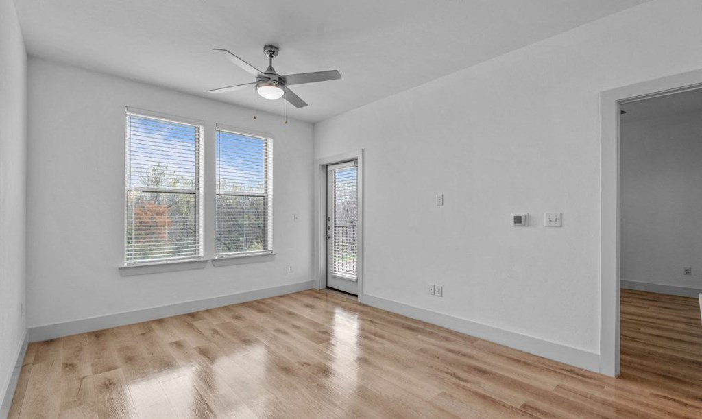 the living room of an empty home with white walls and wood floors