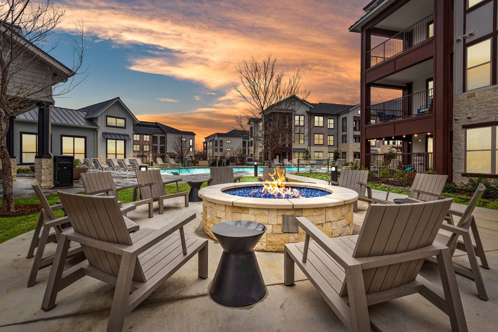 an outdoor patio with a fire pit and chairs at dusk