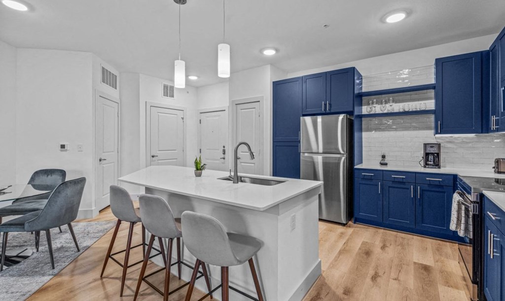 a kitchen with blue cabinets and a white counter top and a stainless steel refrigerator