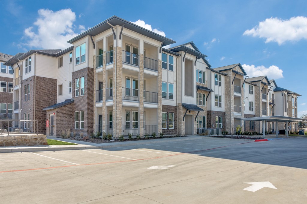 A large apartment complex with a parking lot in front.