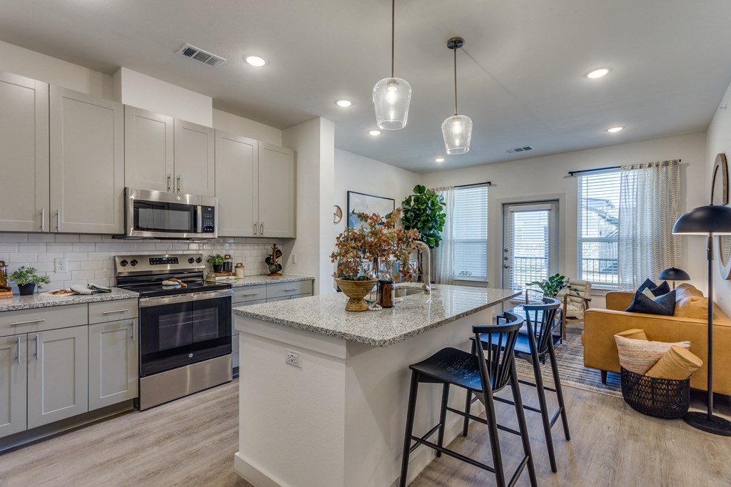 A modern kitchen with a large island and a dining area.