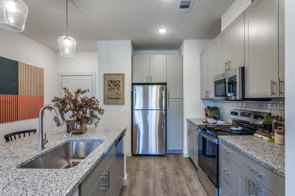 A modern kitchen with a stainless steel refrigerator and a wooden floor.