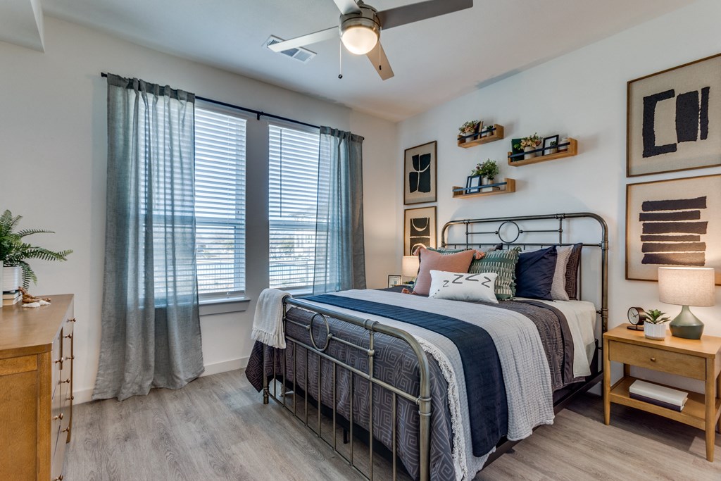 A bedroom with a bed, a nightstand, and a ceiling fan.