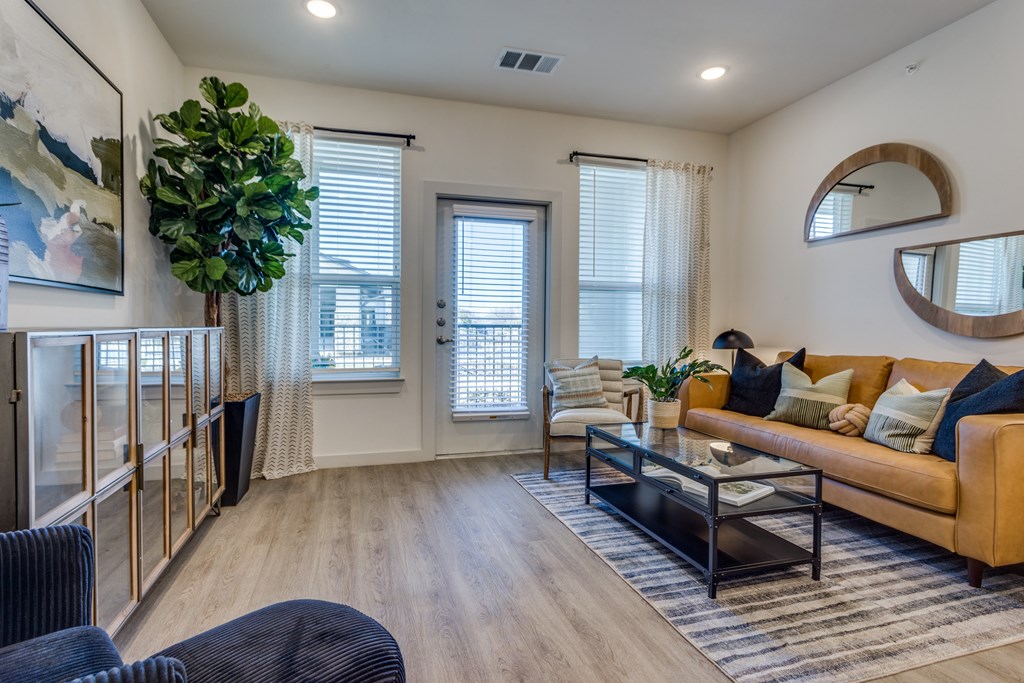 A living room with a couch, chair, and a potted plant.