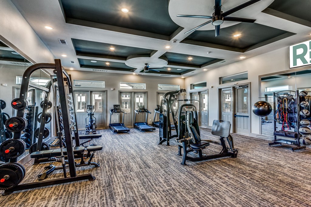 A gym with a variety of equipment including weights and cardio machines.