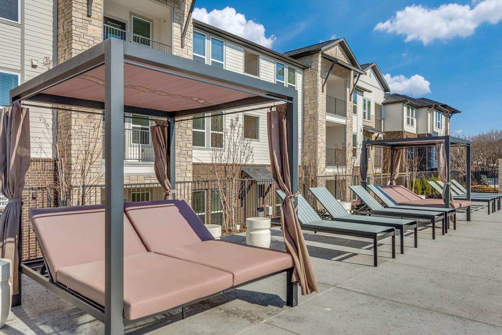 A row of sun loungers are set up in front of apartment buildings.