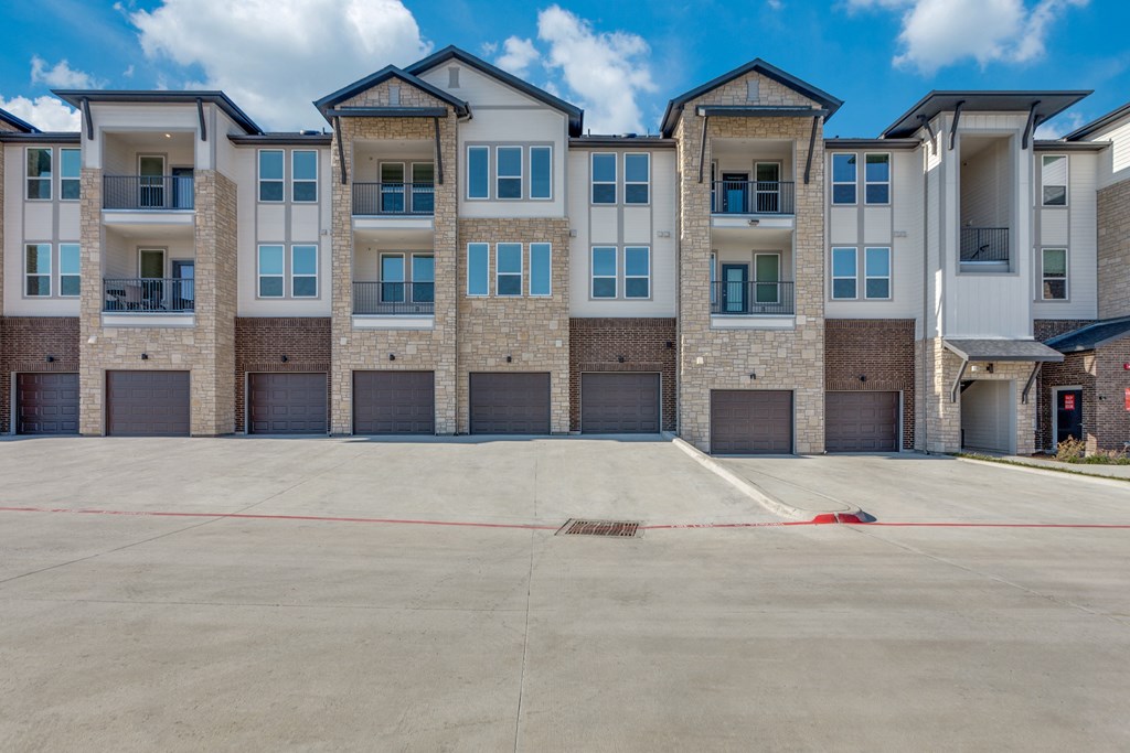 A large, empty parking lot in front of a multi-story apartment building.