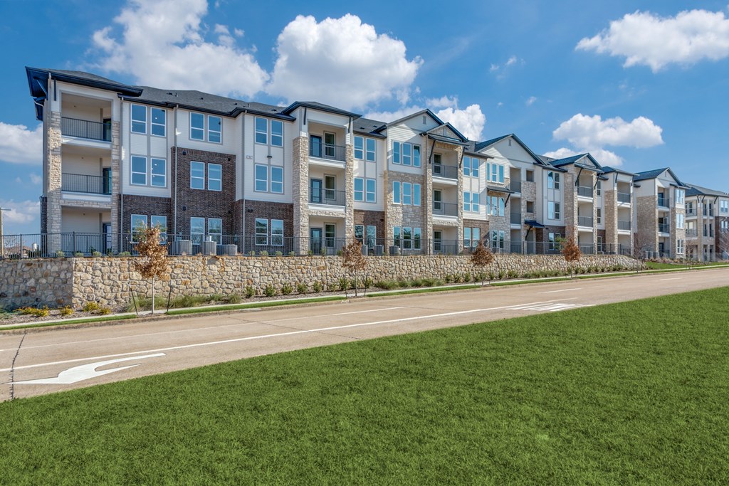 A row of modern apartment buildings with a grassy area in front.