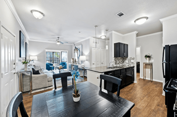 A black table with a plant on it sits in the middle of a white kitchen.