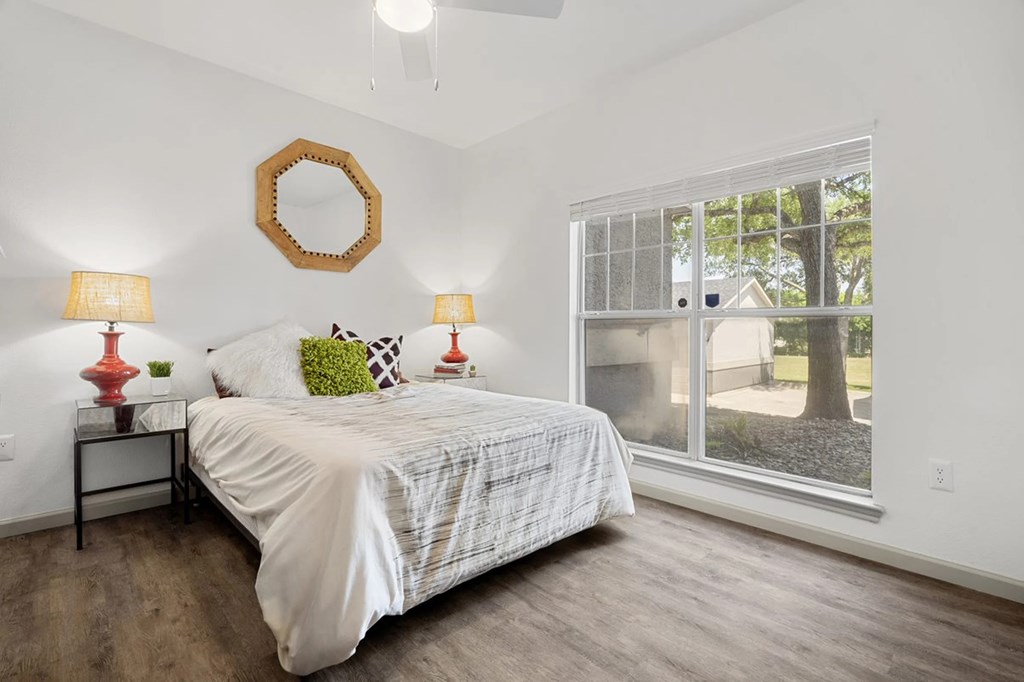 A bedroom with a bed, two lamps, and a mirror on the wall.