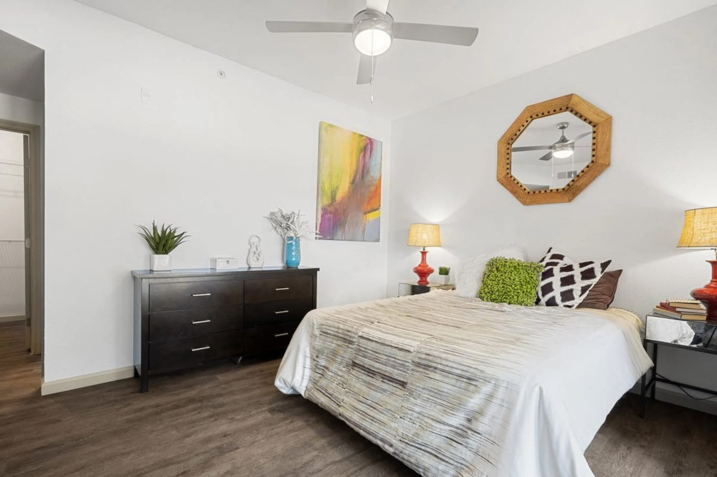 A bedroom with a bed, dresser, and ceiling fan.