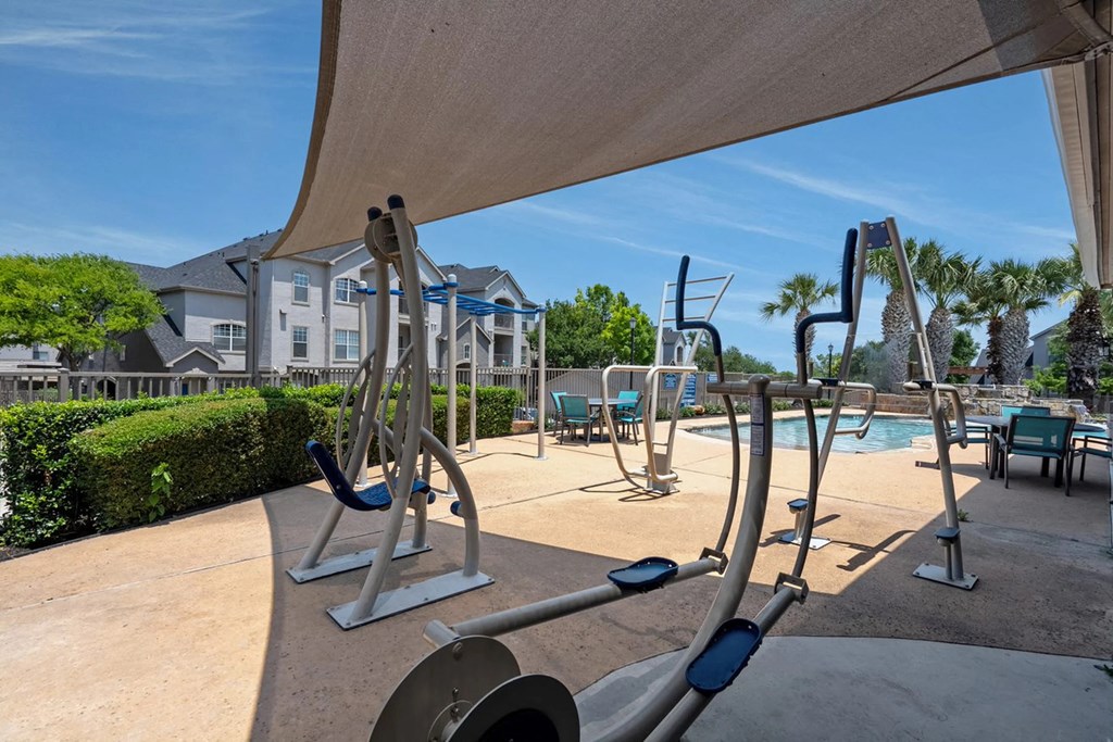 A gym with exercise equipment and a pool in the background.