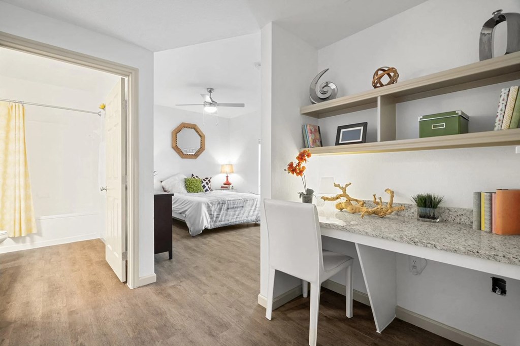 A white chair is in front of a desk with a laptop on it.
