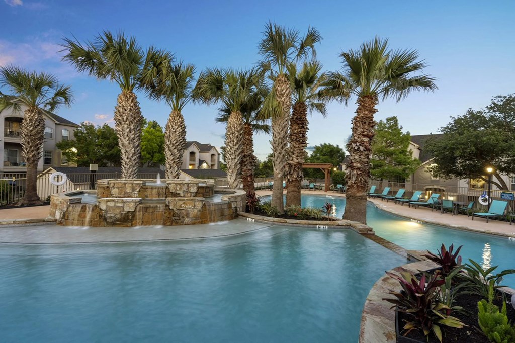 A pool surrounded by palm trees and a waterfall.