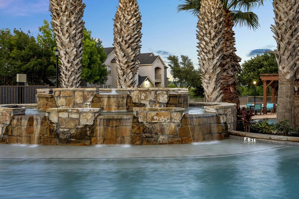 A pool with a waterfall and palm trees in the background.