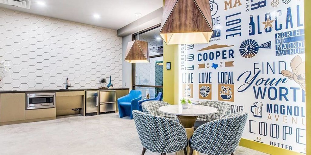 A dining area with a white table and chairs in front of a wall with a patterned design.