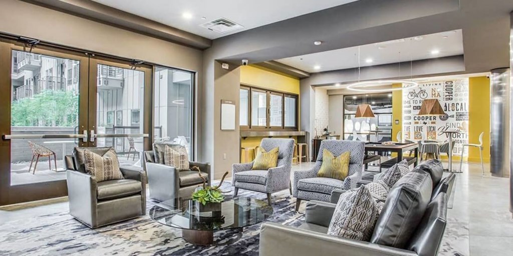 A living room with grey and yellow accents and a glass table.