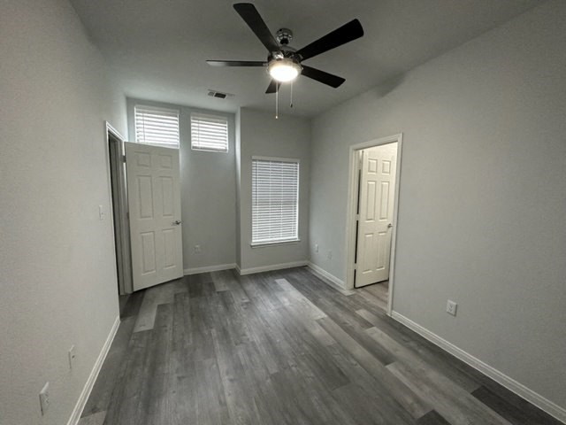 an empty living room with a ceiling fan and doors