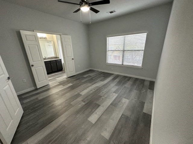 an empty living room with wood floors and a ceiling fan