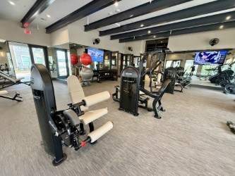 A gym with a variety of equipment including treadmills, weights, and exercise machines.