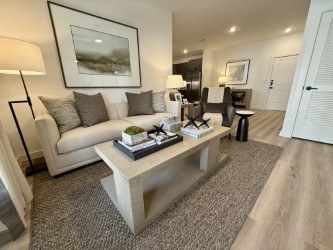 A living room with a white couch, a coffee table, and a painting on the wall.