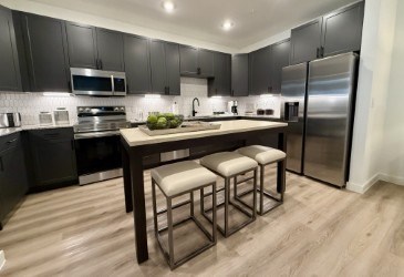 A modern kitchen with a wooden table and bar stools.
