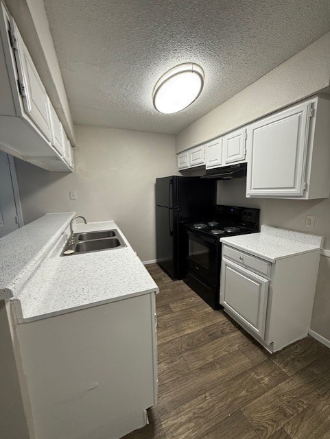 A small kitchen with a black refrigerator and white cabinets.