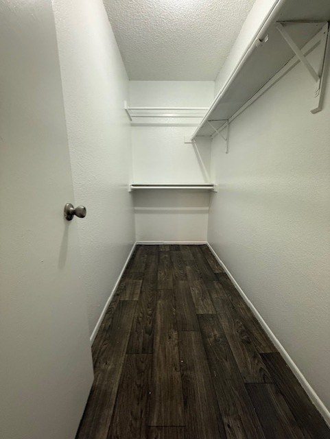 A long, narrow hallway with wood flooring and white walls.