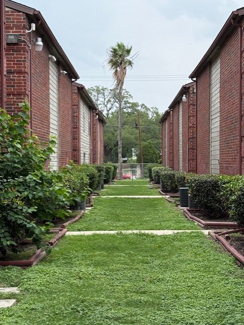 A long row of red brick buildings with green bushes in front.