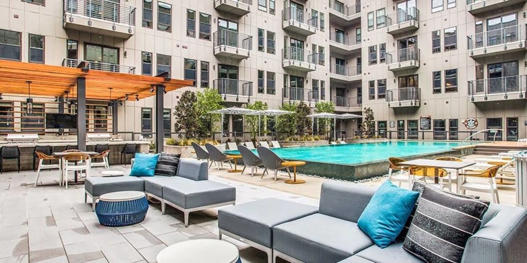 A large outdoor area with a pool, lounge chairs, and a wooden pergola.