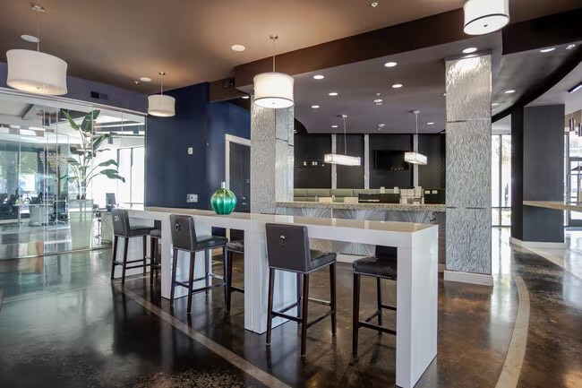 A modern bar with a white counter and black stools.