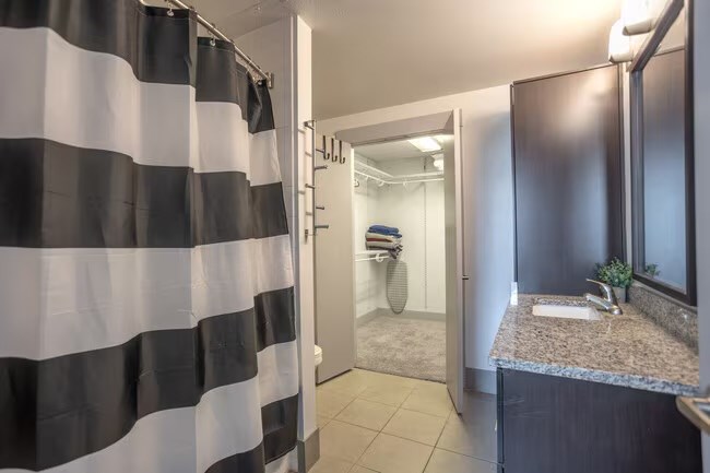 A bathroom with a black and white striped shower curtain.