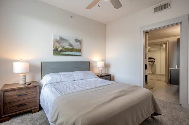 A bedroom with a bed, nightstands, and a painting on the wall.