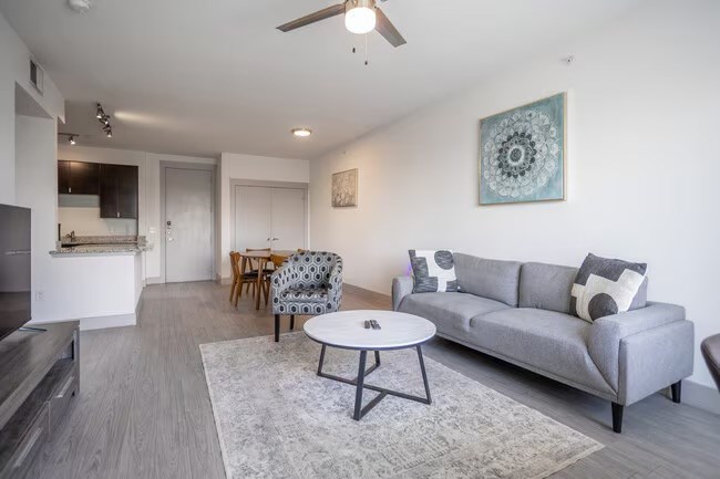 A living room with a grey couch, a coffee table, and a ceiling fan.