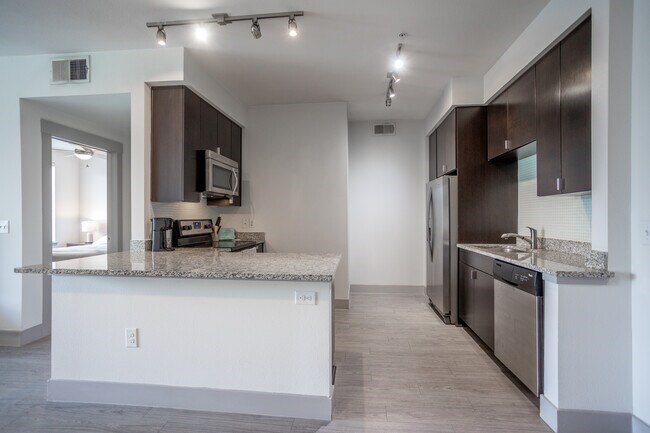 A kitchen with a granite counter top and stainless steel appliances.