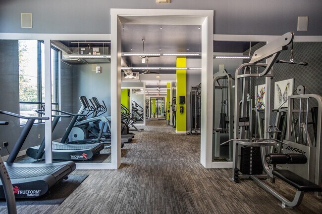 A gym with a variety of equipment including treadmills, weights, and exercise machines.