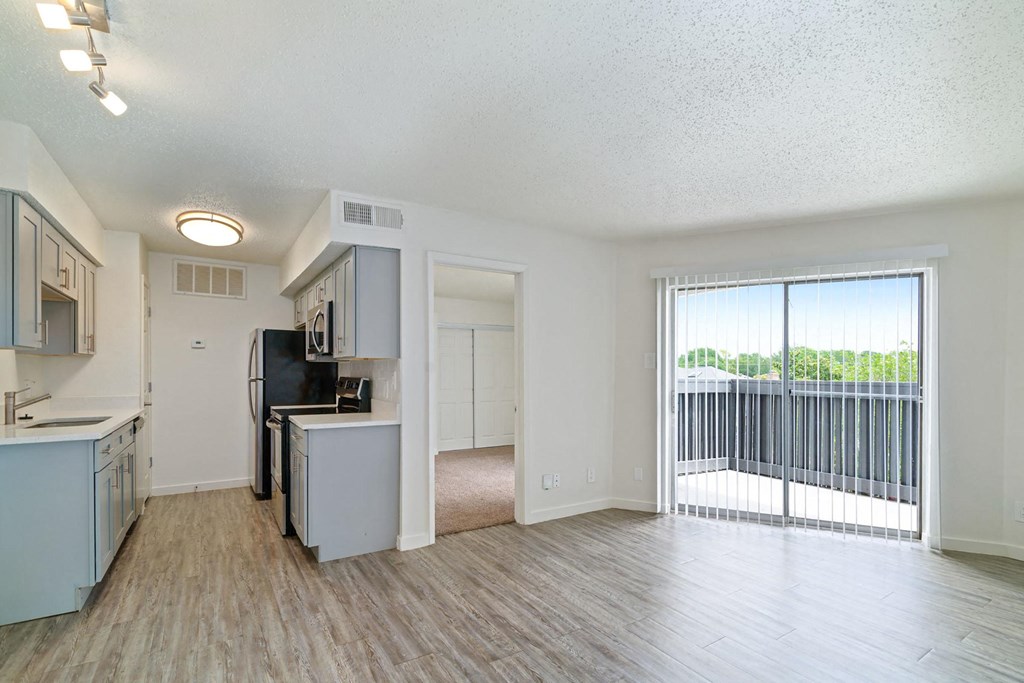 a kitchen and living room with a sliding glass door leading to a balcony